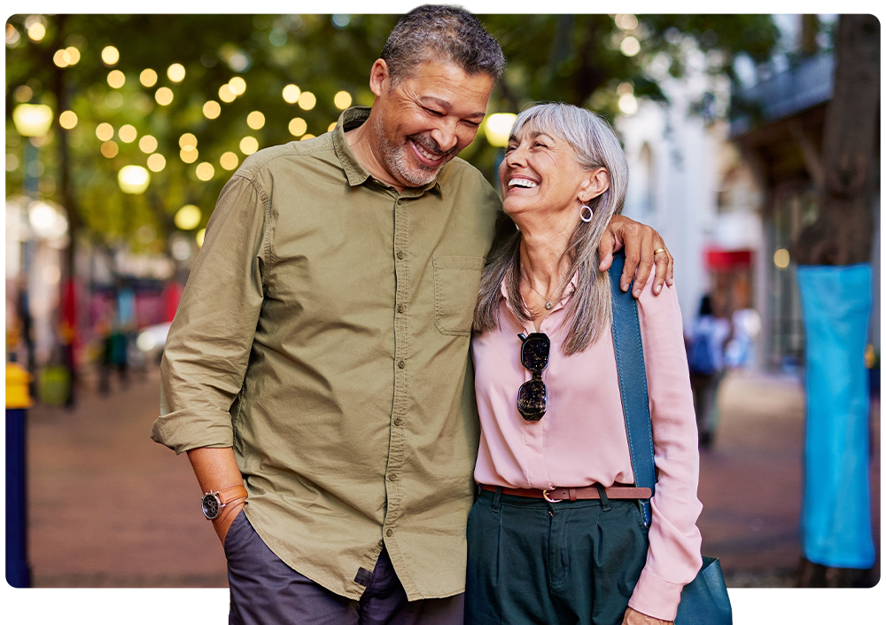 An older couple laughing together on an evening walk downtown