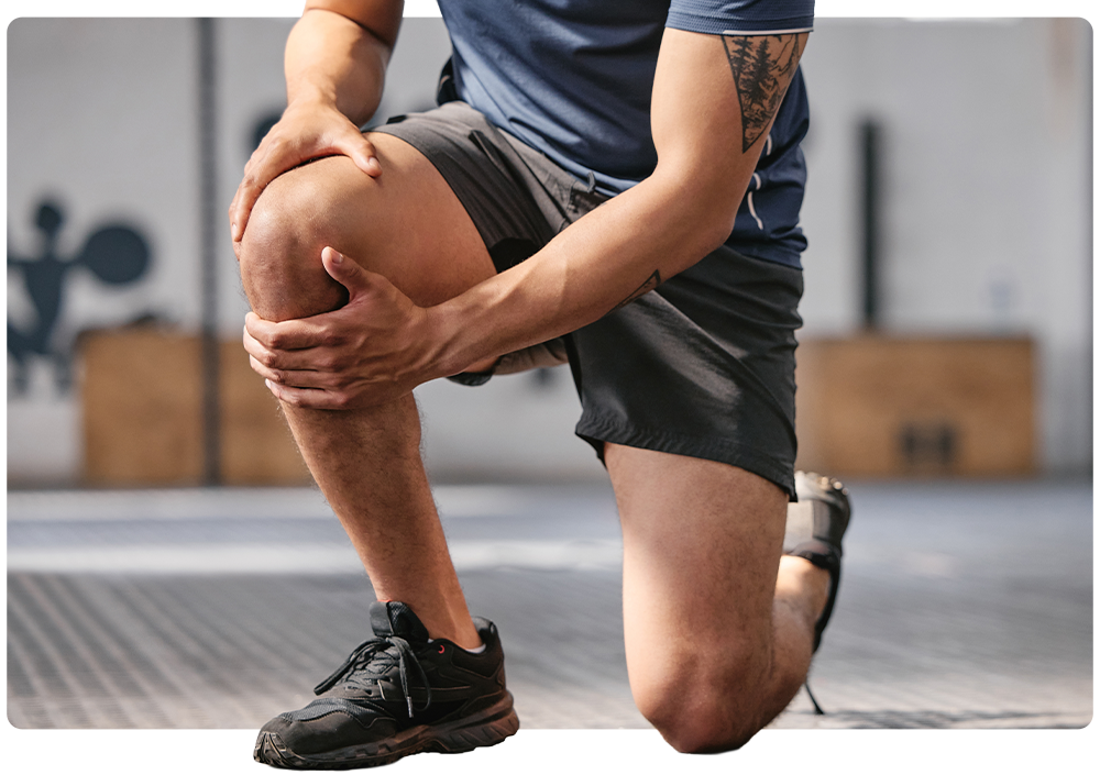 A man kneeling and holding his knee during a workout