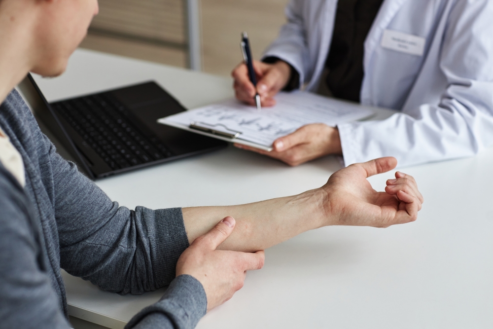 Patient showing arm to doctor during a medical consultation.