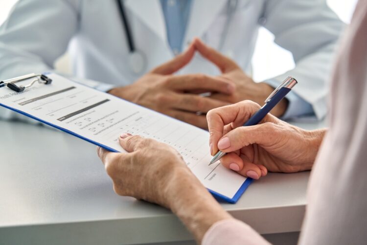 GPT Patient filling out a medical form while talking to a doctor.
