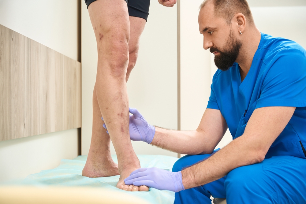 Healthcare professional examining a patient's leg for peripheral artery disease, with a focus on the lower leg during a medical assessment.