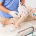 A doctor examining an elderly woman's legs before a varicose vein treatment.